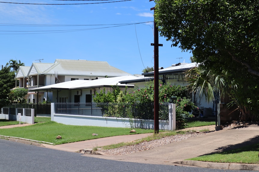 A house on a sunny street, with a tree to the right.