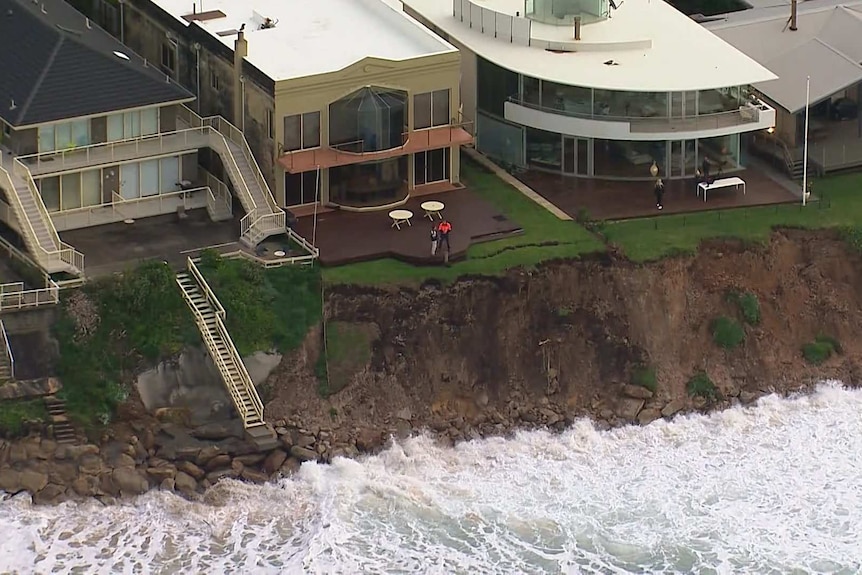 Two people survey the erosion of the land near the coast