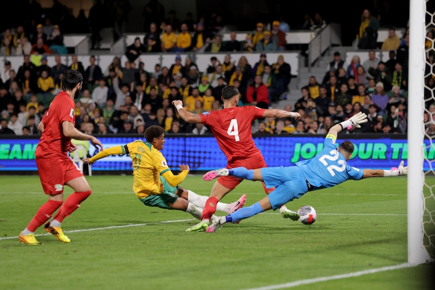 Kusini Yengi kicks the ball towards the goal past two Palestinian defenders and a goalkeeper