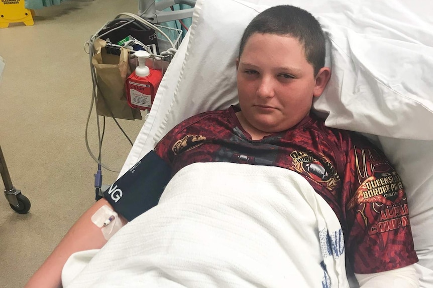 14-year-old Ryan Jackson in Cairns Hospital with a bandage on his arm.
