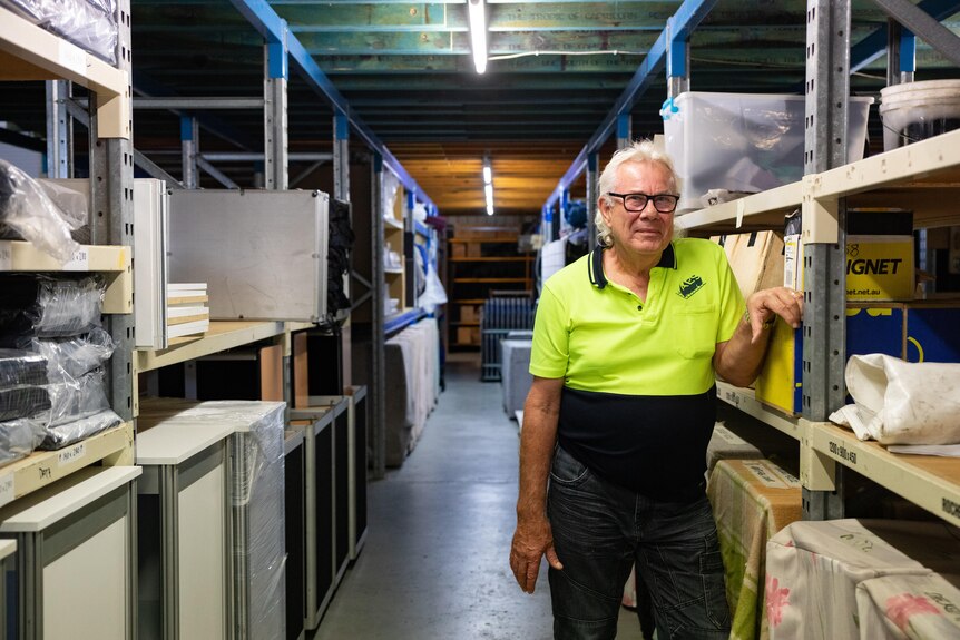 Edward Schimmel leaning on shelving in his warehouse.