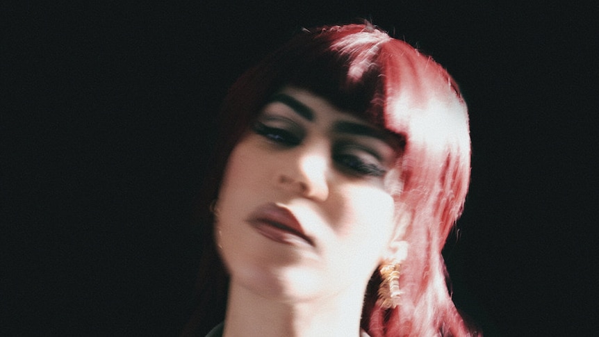 A blurry closeup of a woman with red hair. She looks sleepy. The background is black.