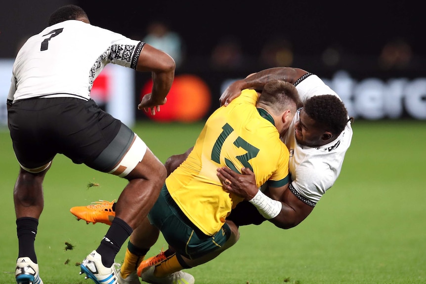 A male rugby union player is tackled by his opponent as he heads towards the ground.