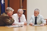 From left: Day, Morrison and McCormack sit pouring over documents at a table