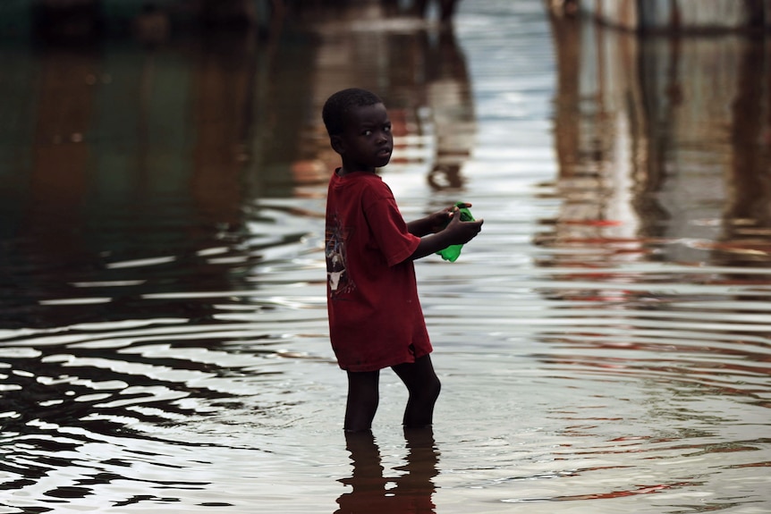 A child walks outside of his flooded home in Haiti (Getty Images: Spencer Platt)