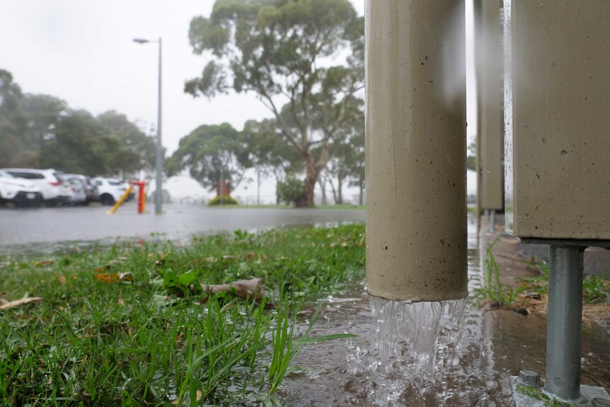 Rain coming out of a spout into a lake in a carpark