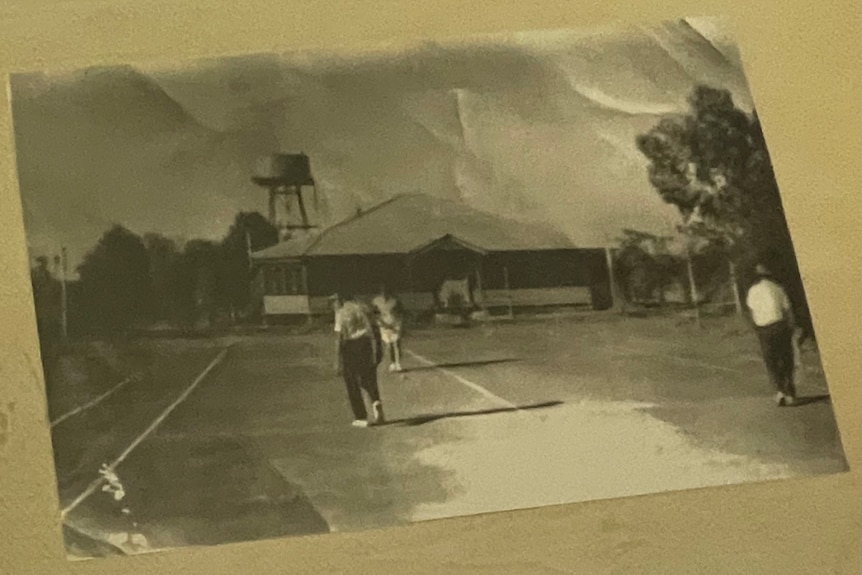 A black and white photo of an old homestead with a tennis court 