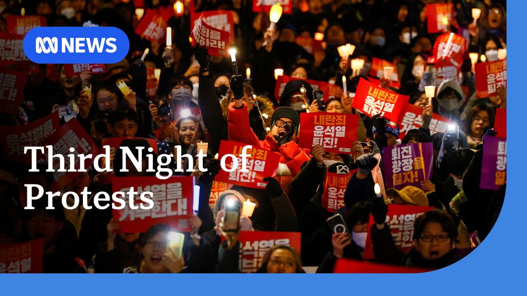 Third Night of Protests: People holding red protest placards with Korean script on them.