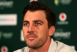 An Australian male cricketer looks on at a media conference.