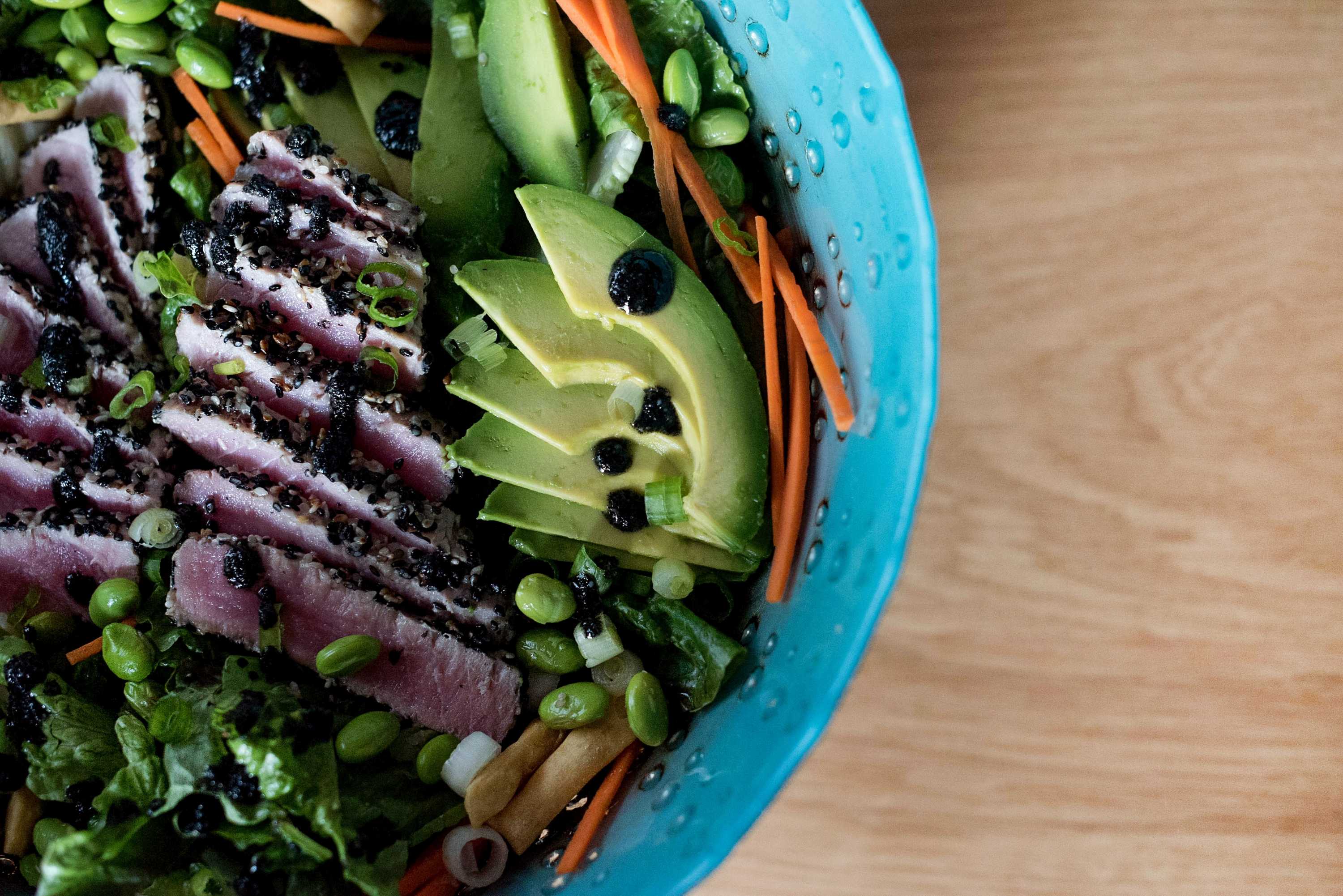 A salad with edamame beans, strands of carrot, lightly seared tuna and slices of avocado