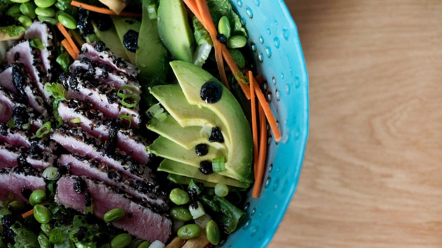 A salad with edamame beans, strands of carrot, lightly seared tuna and slices of avocado