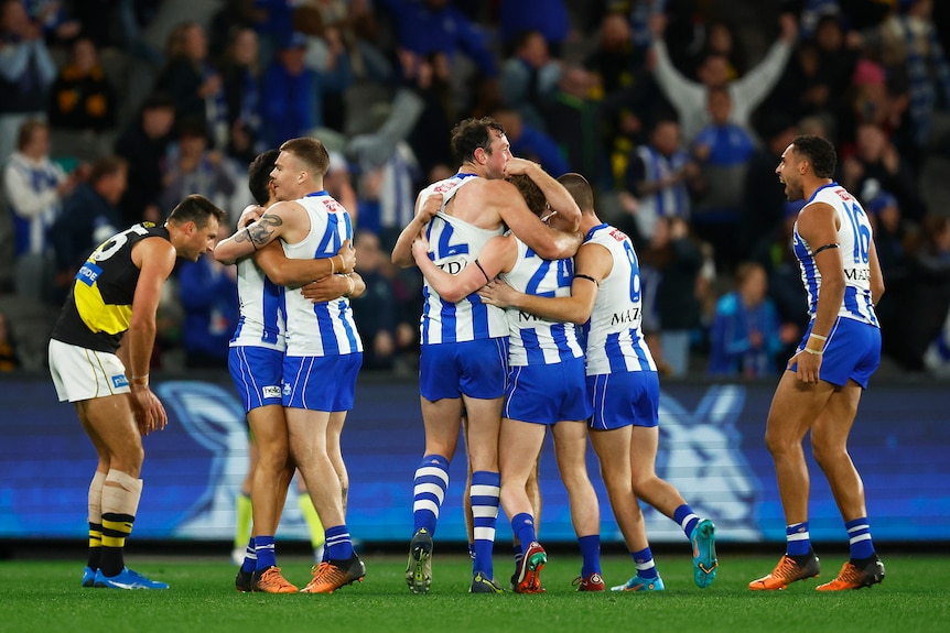 North Melbourne players hug each other on the field