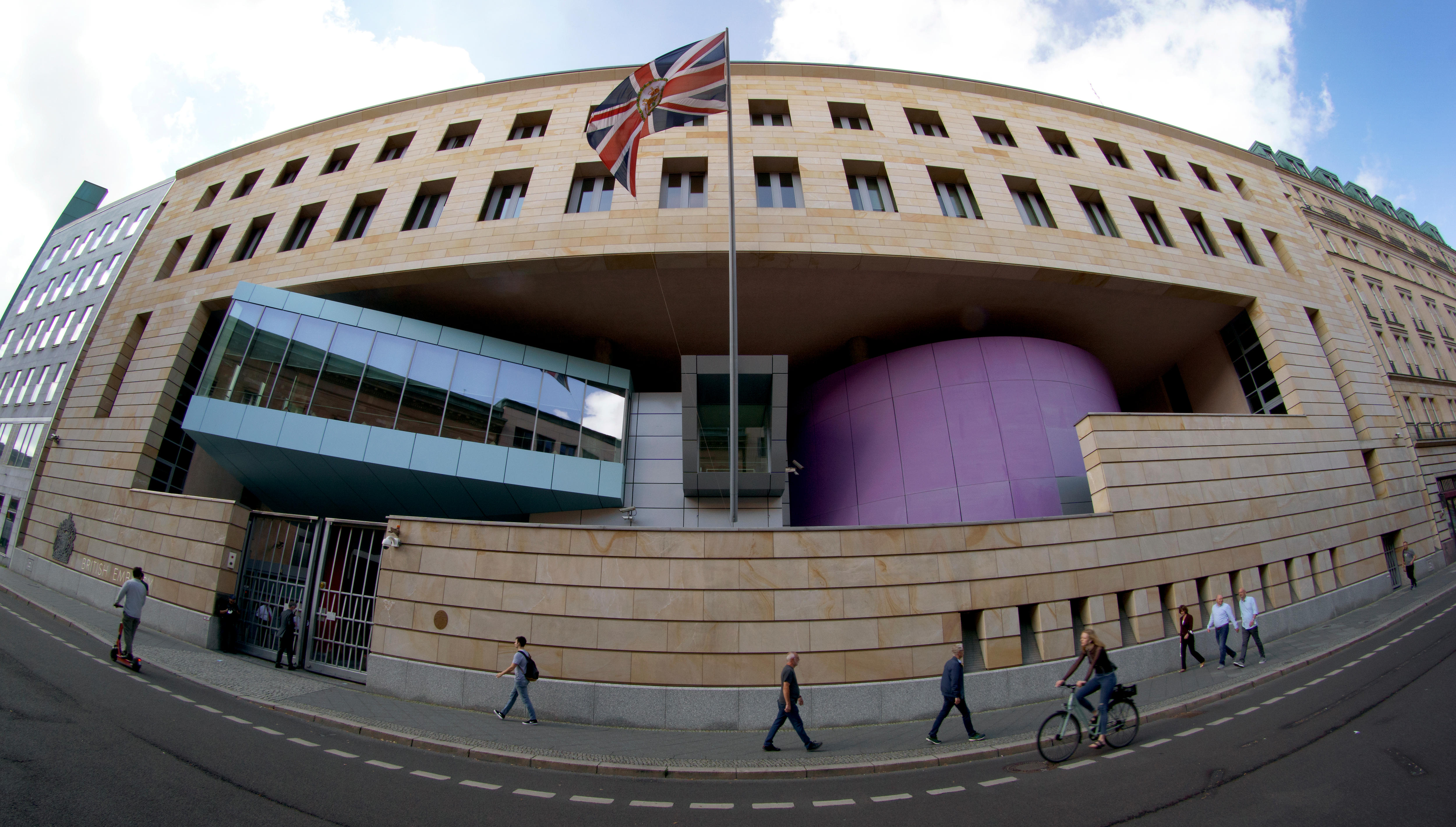 a big embassy building with people walking past