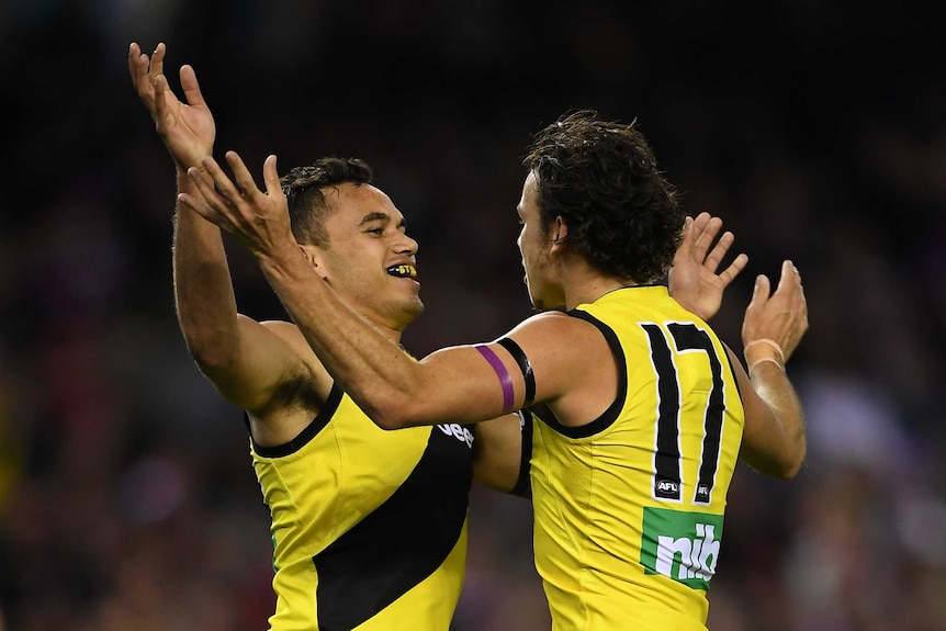 Two AFL teammates celebrate a goal.