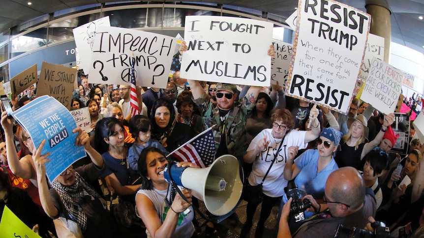 Demonstrators gather outside Los Angeles International Airport holding posters and megaphones