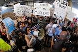 Demonstrators gather outside Los Angeles International Airport holding posters and megaphones