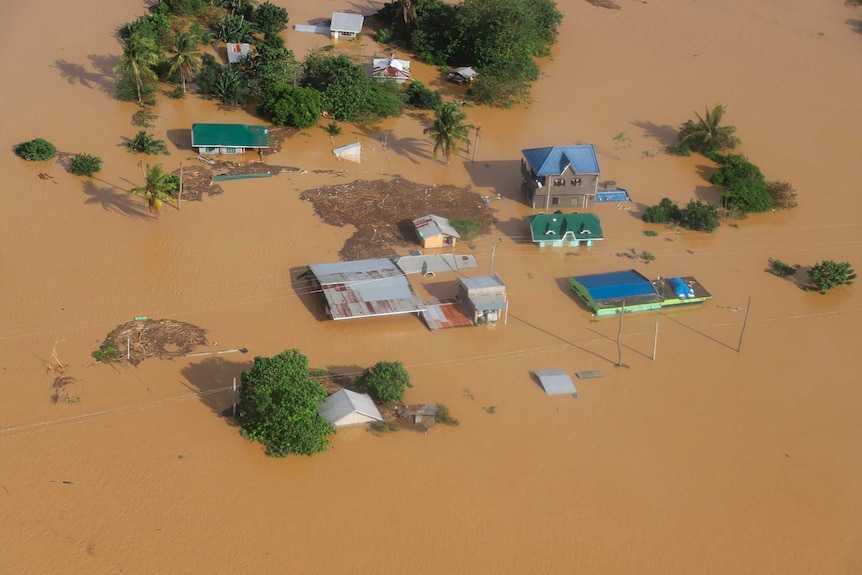 Houses are submerged in brown floodwaters