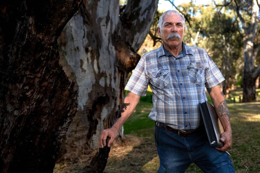 A man leans against a gum tree.