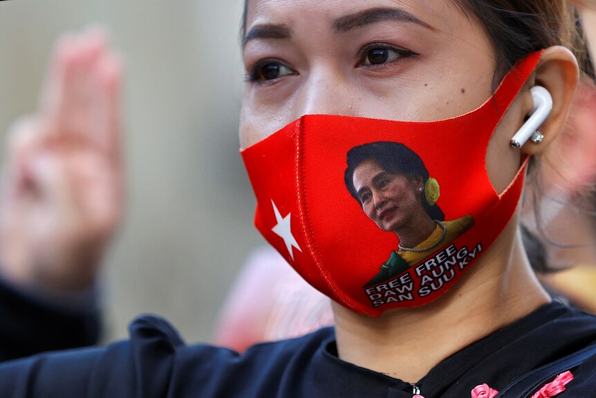 A protester uses a face mask with an image of deposed Myanmar leader Aung San Suu Kyi 
