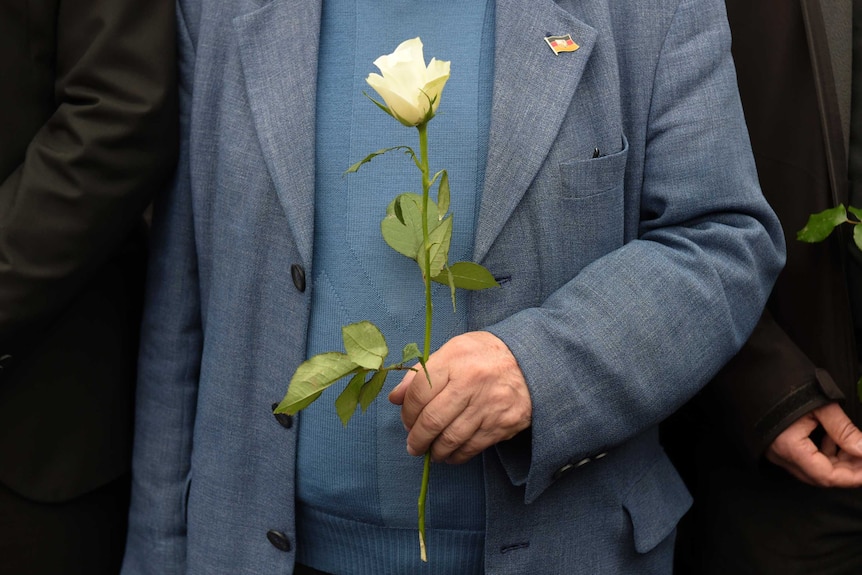 A man holds a white rose as he participates in the march.