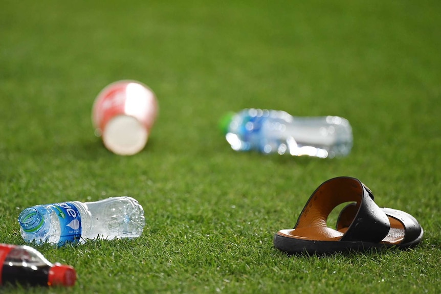 A sandal is shown on grass with empty plastic bottles alongside it