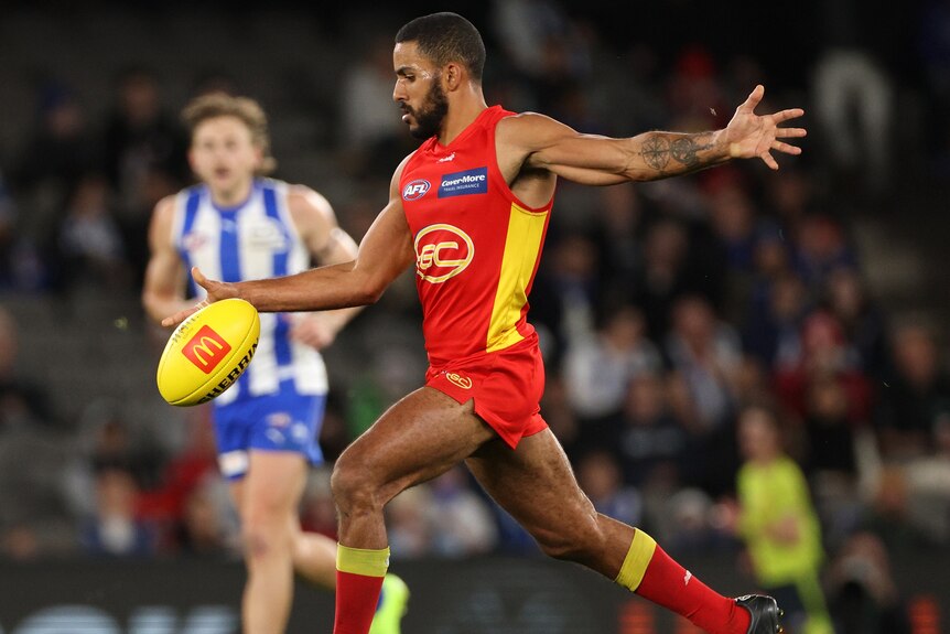 A Gold Coast Suns AFL player prepares to kick the ball with his right foot during a match.