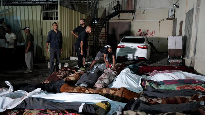 Palestinians check the bodies of their relatives killed outside al-Aqsa Martyras hospital 