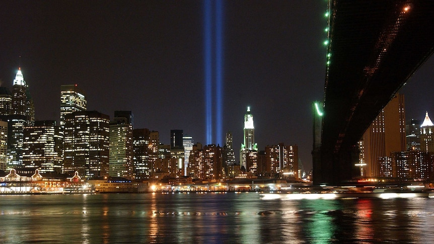 two beams of blue light emanate from the New York Skyline in the position of the Twin Towers
