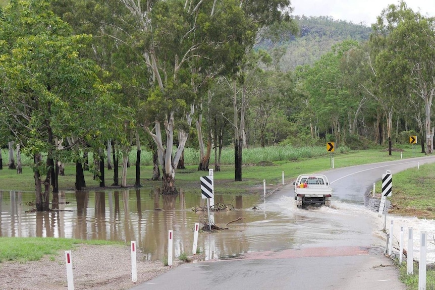 A car drives through water rushing over the road.