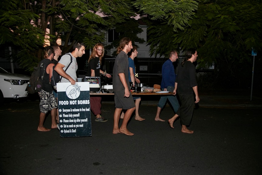 The table, laden with food, is carried a short distance from the community house to the park, where it is served to locals.