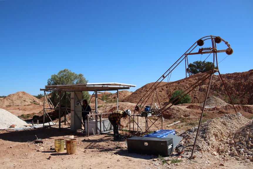 The top of a mine- solar panels and a hoist surrounded by red soil in piles. 