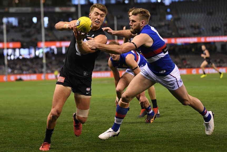 Patrick Cripps makes a handpass while under pressure from Jackson Trengove.