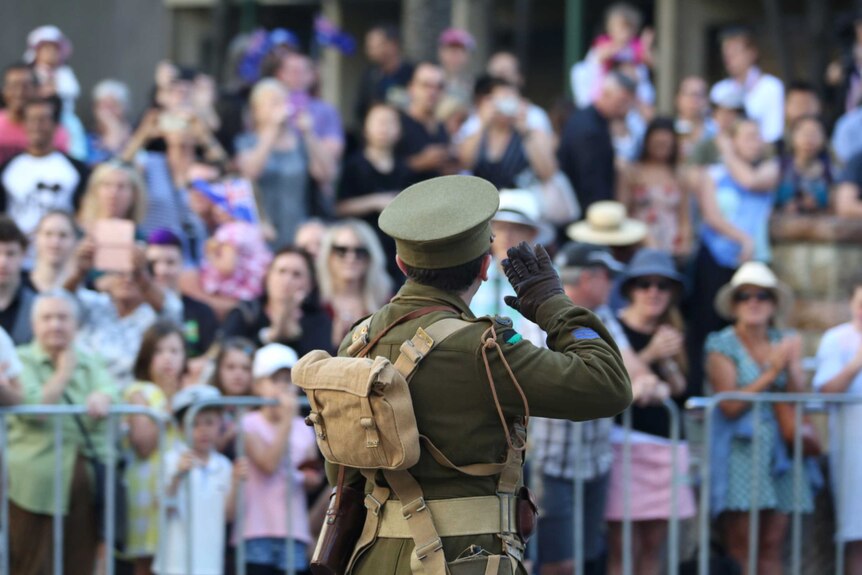 A person dressed as a soldier from World War 1 salutes the Shrine of Remembrance in the Brisbane Anzac Day march.
