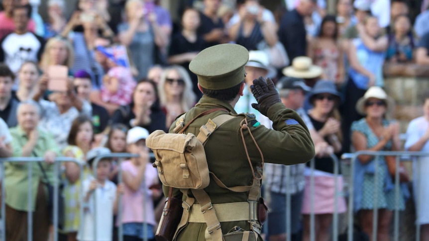 A person dressed as a soldier from World War 1 salutes the Shrine of Remembrance in the Brisbane Anzac Day march.