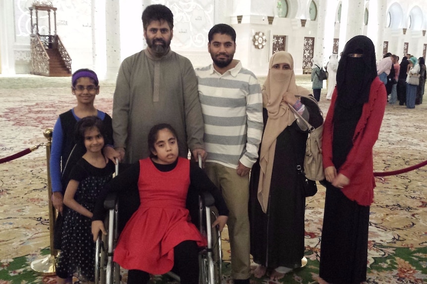 A girl in a wheelchair surrounded by her family