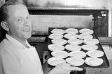 Pastry cook holds a tray of Australian meat pies