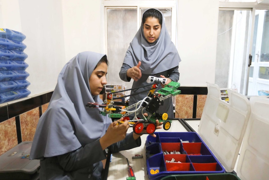 Two Afghan teenage girls work on a robotics project.
