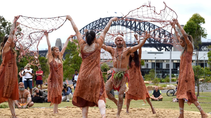Aboriginal dancers perform the WugulOra Morning Ceremony with the Sydney Harbour Bridge in the distance.