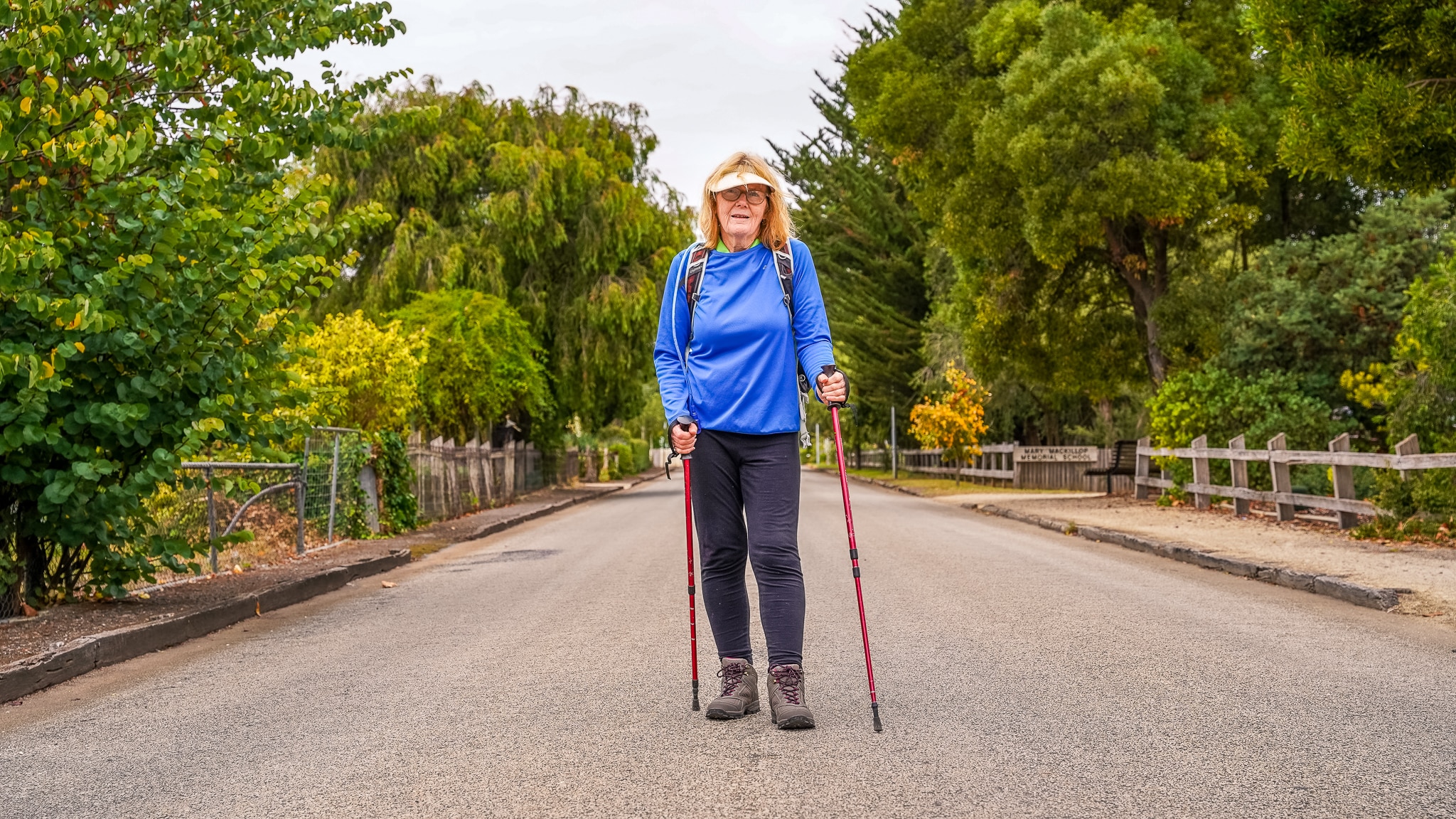 A woman walking down a path with hiking poles