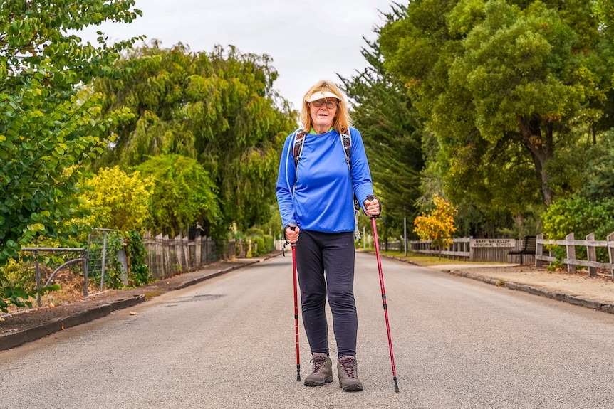 A woman walking down a path with hiking poles