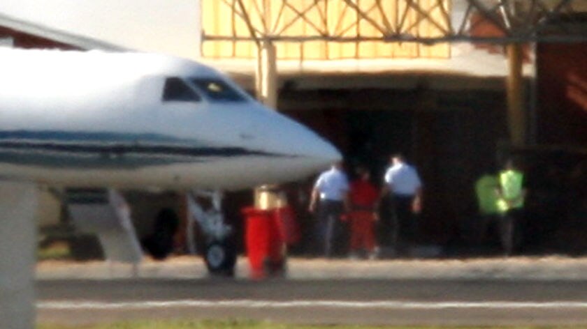 Homecoming: David Hicks (in red overalls) is escorted off the plane in Adelaide.