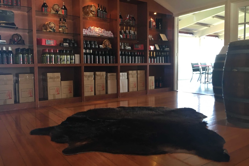 A cattle hide on the floor, wine barrels and bottles of wine in shelves.