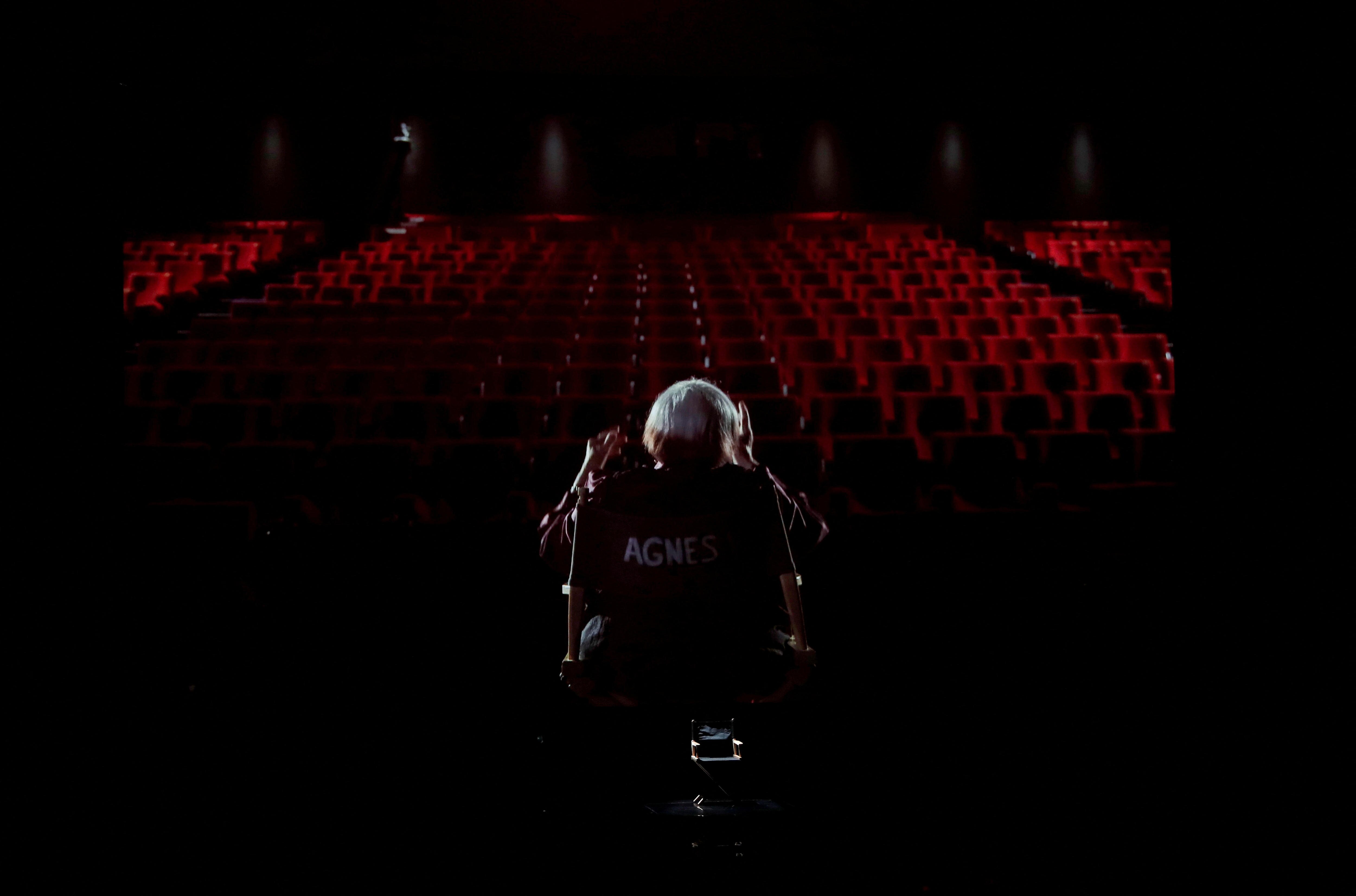 A person sitting in a seat in front of a large theatre. 