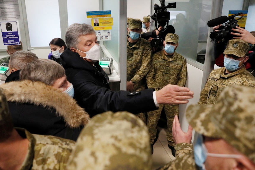 Man stands in airport surrounded by soldiers 