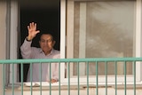Hosni Mubarak waves to supporters from a hospital room.