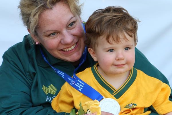 Natalie Smith with her toddler son Daniel on her lap showing her silver medal.