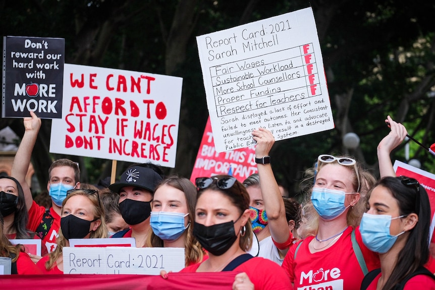 People wearing masks hold protest signs