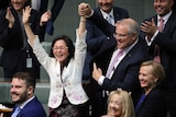 Scott Morrison holds Gladys Liu's arm in the air as he points to her with his other hand. MPs behind are smiling and clapping
