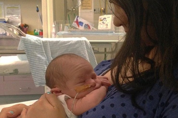 A woman with a tiny baby with a tube in its nose