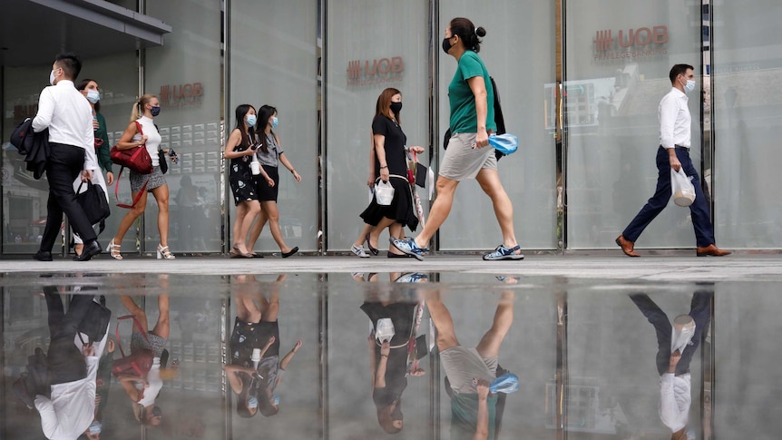 Office workers wearing protective face masks walk in Singapore's central business district.